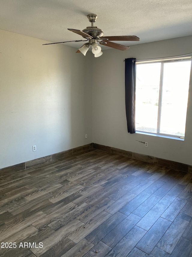 empty room with dark wood-style floors, ceiling fan, a textured ceiling, and baseboards