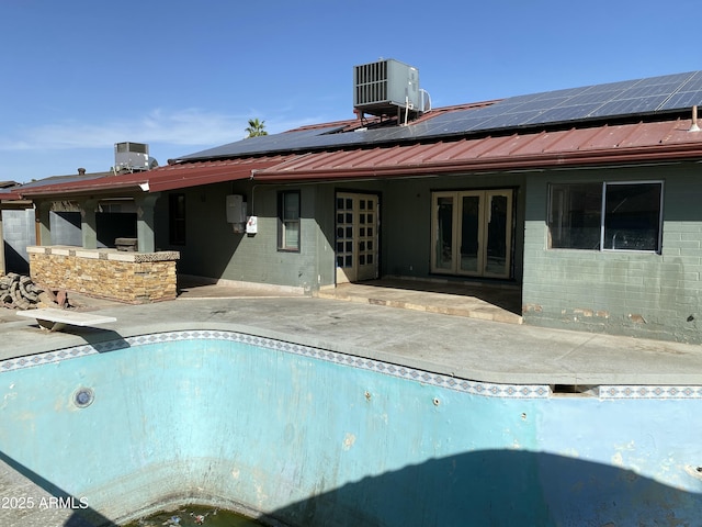 view of swimming pool with french doors, a patio, central AC unit, an empty pool, and a diving board