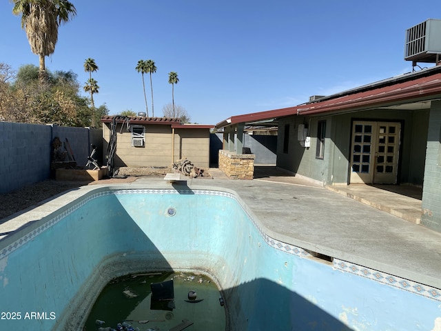 view of swimming pool featuring a fenced in pool, a fenced backyard, a patio, and central AC unit