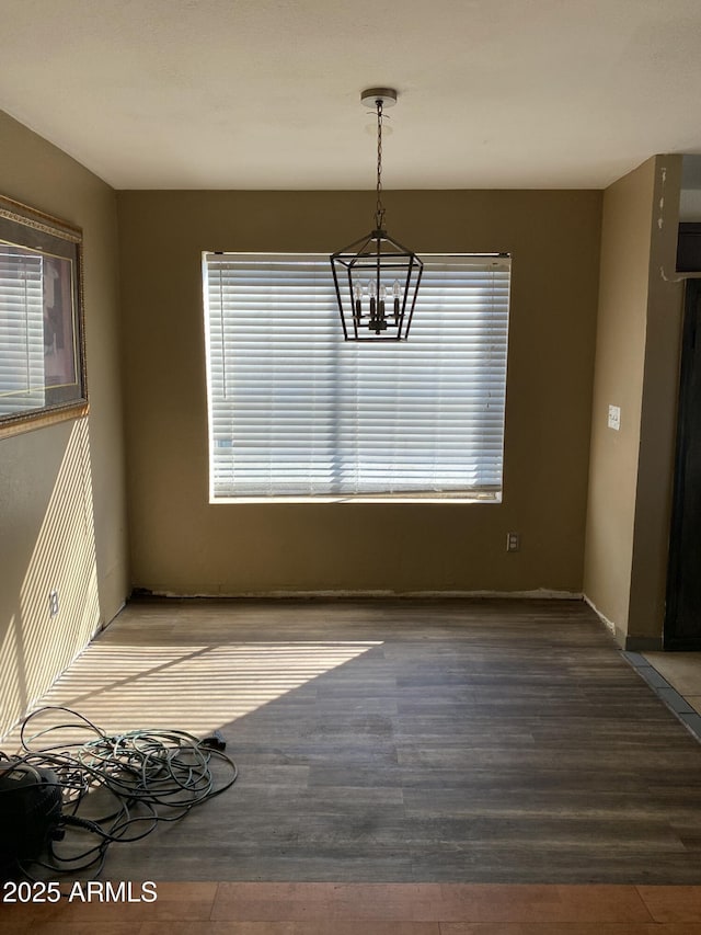 unfurnished dining area with wood finished floors and an inviting chandelier