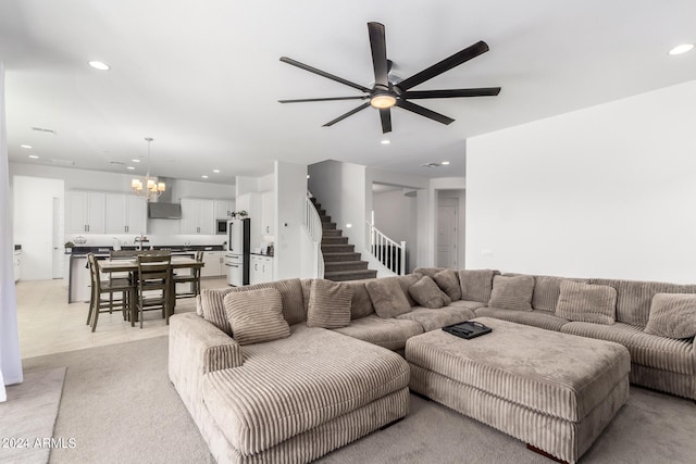 living room featuring light carpet and ceiling fan with notable chandelier