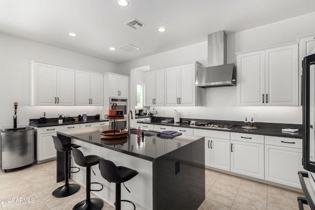 kitchen featuring white cabinetry, wall chimney exhaust hood, and a kitchen island