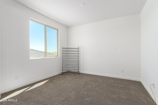 spare room featuring dark colored carpet