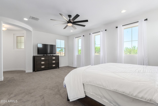 bedroom with ceiling fan, light carpet, and multiple windows