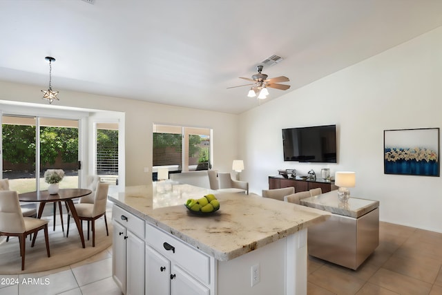 kitchen featuring vaulted ceiling, pendant lighting, a center island, white cabinetry, and light tile patterned flooring