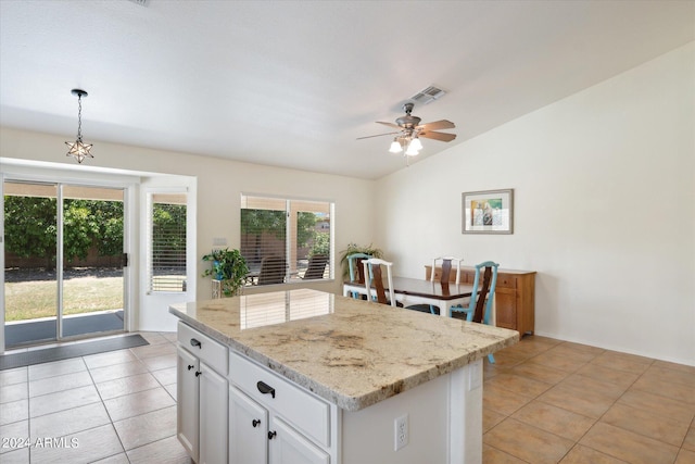 kitchen with pendant lighting, a center island, lofted ceiling, light tile patterned flooring, and white cabinetry