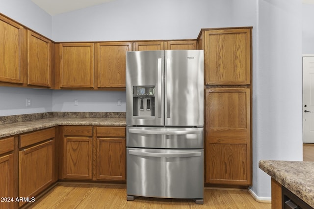 kitchen featuring stainless steel fridge with ice dispenser, light hardwood / wood-style floors, and vaulted ceiling