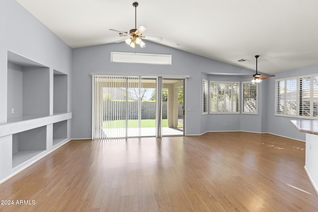 unfurnished living room with ceiling fan, built in features, lofted ceiling, and light hardwood / wood-style flooring