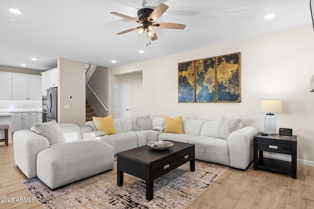 living room with light wood-type flooring, a ceiling fan, stairs, and recessed lighting