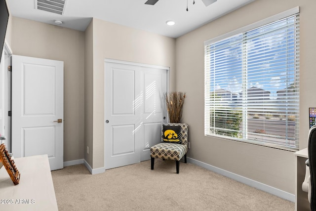living area featuring light colored carpet, a healthy amount of sunlight, ceiling fan, and visible vents