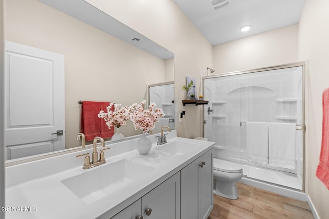bathroom with wood finished floors, visible vents, toilet, and a sink