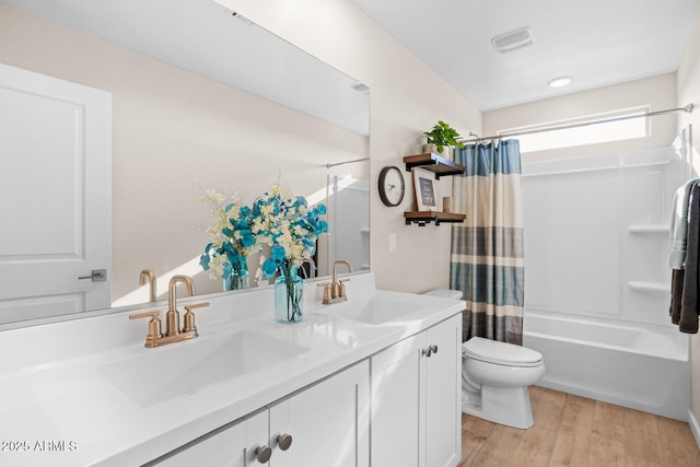bathroom featuring wood finished floors, toilet, double vanity, and a sink