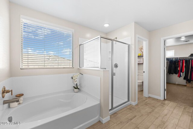 full bath with wood finished floors, toilet, a bath, and a stall shower