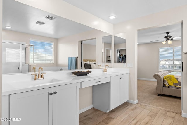 bathroom featuring wood finished floors, ensuite bath, a sink, visible vents, and a ceiling fan