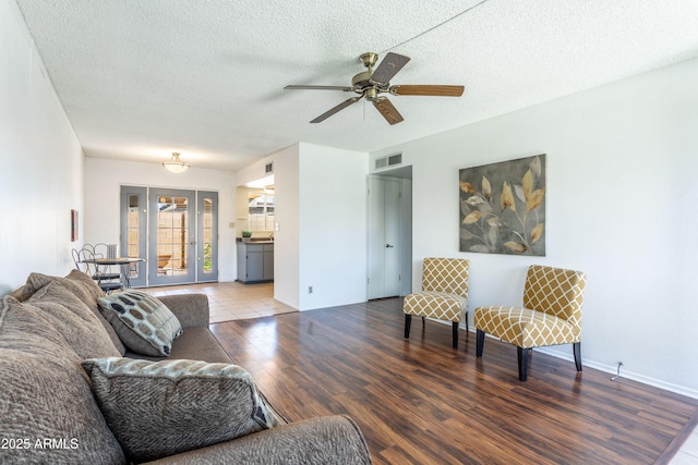 living room featuring ceiling fan, wood-type flooring, and a textured ceiling