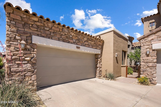 view of front facade featuring a garage, stucco siding, driveway, and stone siding