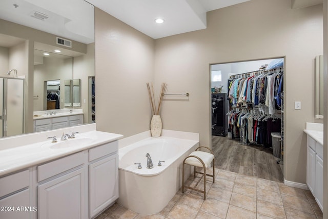 bathroom with visible vents, a spacious closet, a bath, and vanity