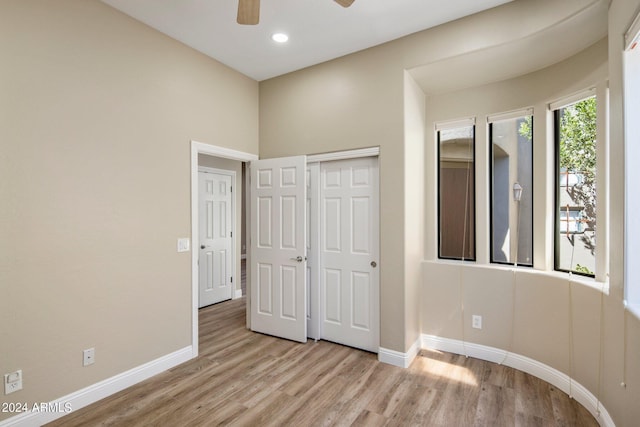 unfurnished bedroom with wood finished floors, a closet, recessed lighting, and baseboards