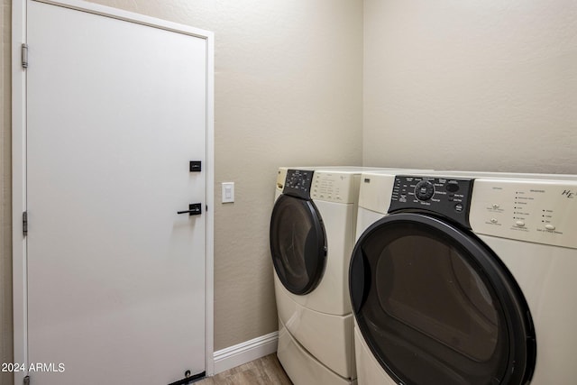 laundry area with washer and dryer, light wood-style flooring, laundry area, and baseboards