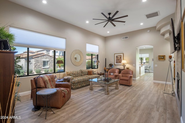living room featuring visible vents, arched walkways, ceiling fan, and light wood-style flooring
