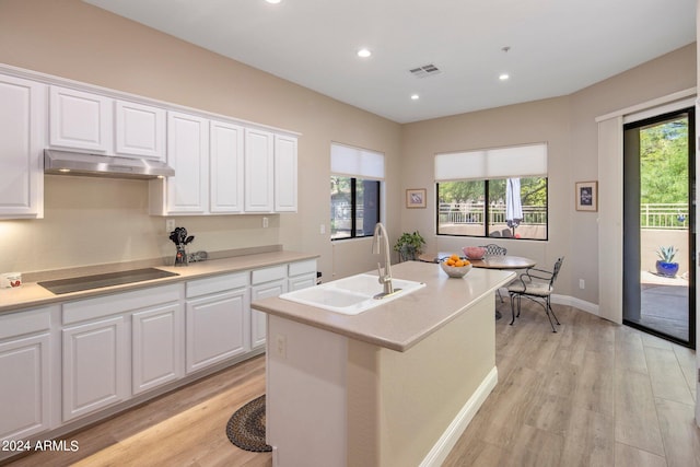 kitchen with a sink, a wealth of natural light, black electric stovetop, and under cabinet range hood