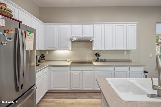 kitchen featuring light wood finished floors, under cabinet range hood, black electric stovetop, white cabinets, and freestanding refrigerator