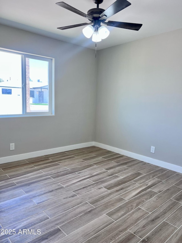 empty room with a ceiling fan, wood finished floors, and baseboards