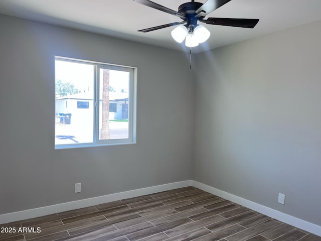unfurnished room with ceiling fan, dark wood finished floors, and baseboards