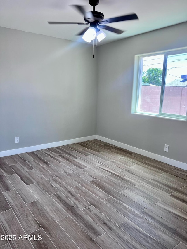 empty room with baseboards, wood finished floors, and a ceiling fan