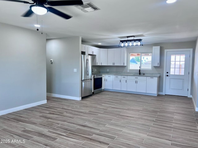 kitchen with appliances with stainless steel finishes, visible vents, baseboards, and a sink