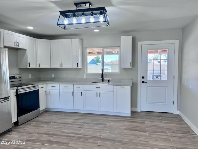 kitchen with wood finish floors, a sink, stainless steel appliances, and light countertops
