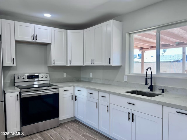 kitchen featuring plenty of natural light, a sink, white cabinets, and stainless steel range with electric cooktop