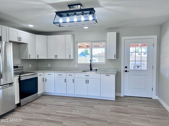 kitchen with recessed lighting, appliances with stainless steel finishes, white cabinets, a sink, and wood tiled floor