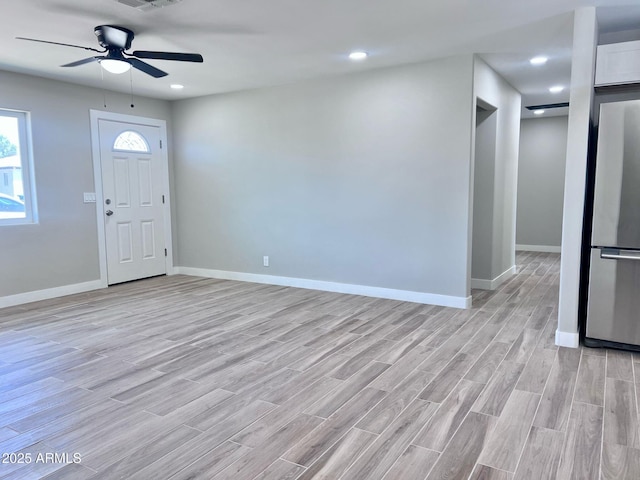 entrance foyer with visible vents, light wood-type flooring, a ceiling fan, and baseboards
