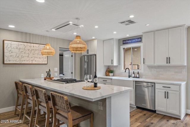 5332 N 81st Pl, Scottsdale, AZ 85250 - kitchen with appliances with stainless steel finishes, wood finished floors, a breakfast bar, light stone counters, and tasteful backsplash