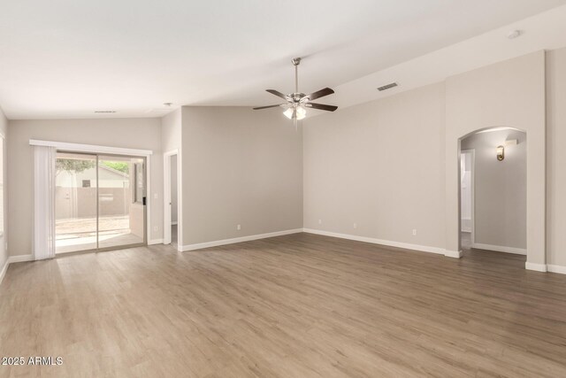 10317 E Kiva Cir, Mesa, AZ 85209 - unfurnished living room featuring baseboards, arched walkways, a ceiling fan, wood finished floors, and lofted ceiling