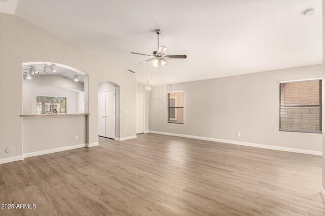 10317 E Kiva Cir, Mesa, AZ 85209 - unfurnished living room with arched walkways, wood finished floors, a ceiling fan, and lofted ceiling