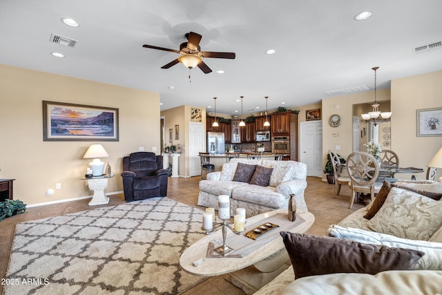 tiled living room with ceiling fan with notable chandelier