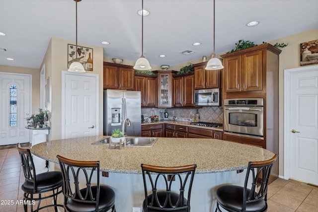 kitchen with a breakfast bar, pendant lighting, sink, light stone counters, and stainless steel appliances