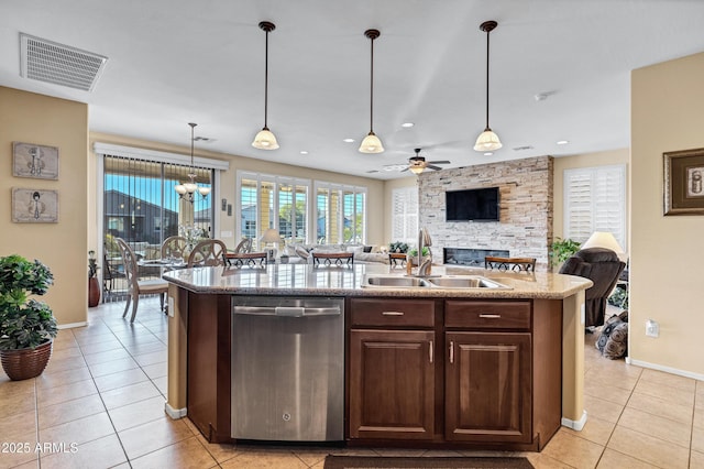 kitchen featuring a fireplace, an island with sink, sink, stainless steel dishwasher, and dark brown cabinetry