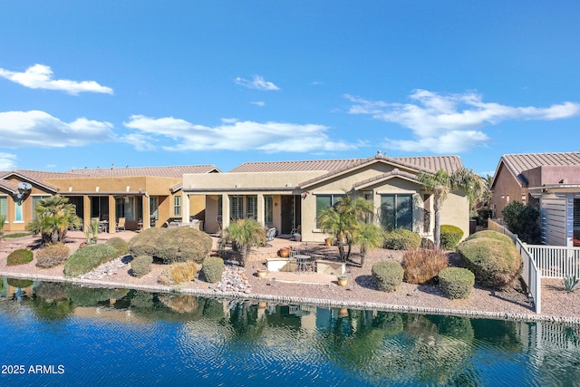 back of property featuring a water view, stucco siding, and a patio