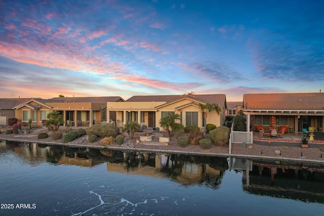 back of property featuring a water view and a patio area