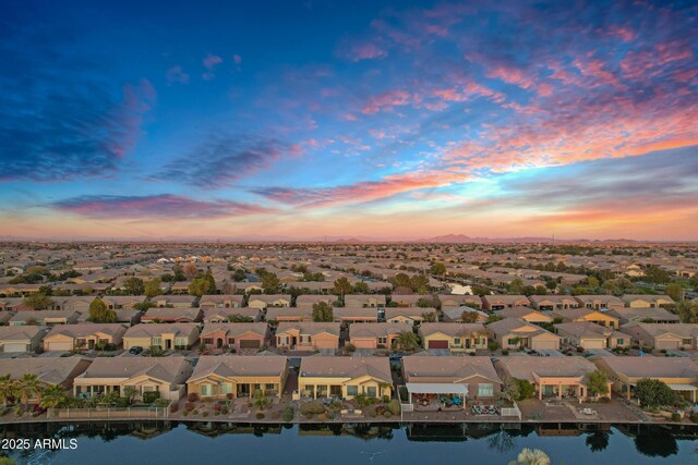 aerial view at dusk with a residential view and a water view