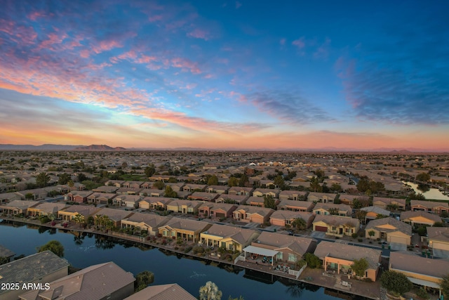 aerial view at dusk with a residential view and a water view