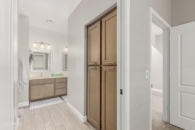 bathroom with wood tiled floor, visible vents, vanity, and baseboards