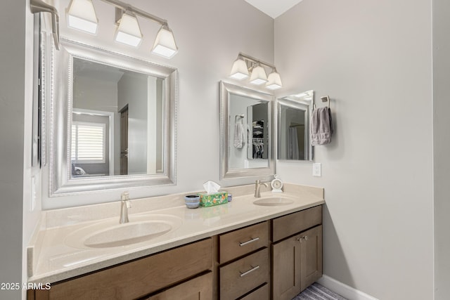 full bath featuring double vanity, a sink, and baseboards