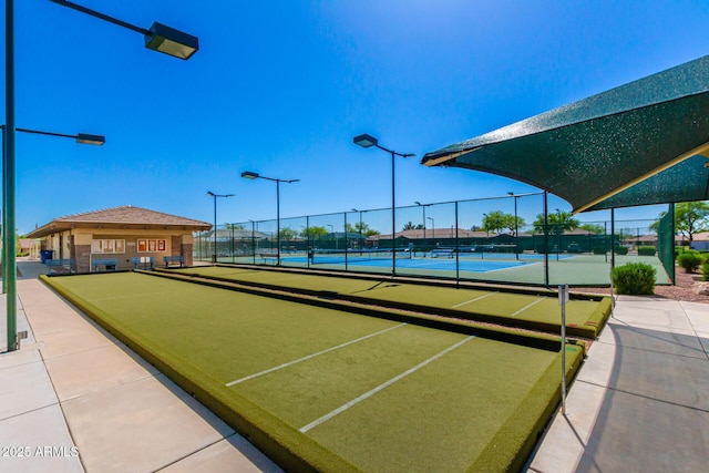 view of property's community with a tennis court and fence