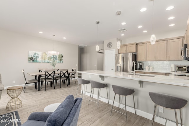 kitchen with stainless steel appliances, light wood-style floors, a sink, and tasteful backsplash