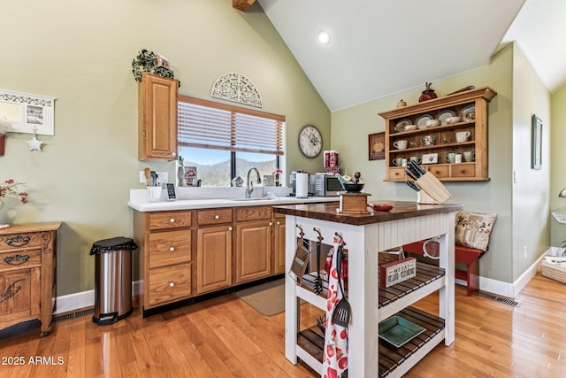 kitchen featuring high vaulted ceiling, sink, and light hardwood / wood-style floors