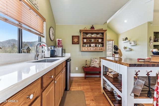 kitchen with vaulted ceiling, butcher block countertops, sink, a mountain view, and light hardwood / wood-style flooring